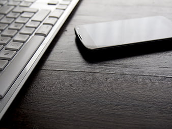 Smartphone and Keyboard on Dark Wooden Desk