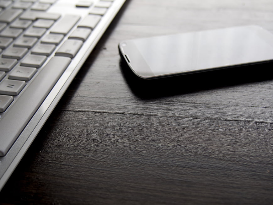 Smartphone and Keyboard on Dark Wooden Desk