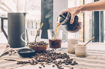 Pouring Hot Coffee into Glass Cup with Beans