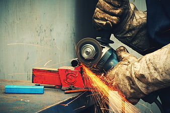 Close-up of worker grinding metal with angle grinder and sparks