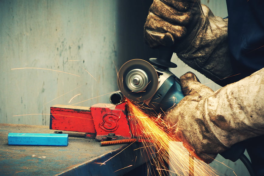 Close-up of worker grinding metal with angle grinder and sparks