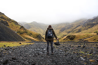 Hiker Walking on Rocky Path in Foggy Mountain Valley