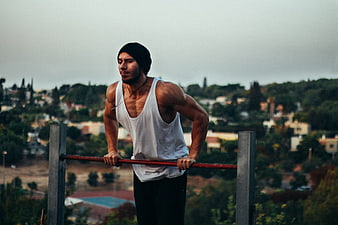 Muscular man doing dips on outdoor parallel bars