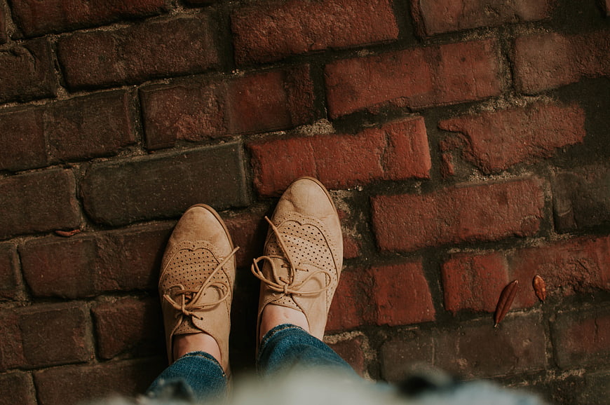 Top-down view of beige brogues on red brick pavement