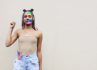 Woman with rainbow face paint and raised fist