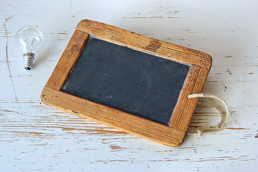 Vintage wooden chalkboard and lightbulb on rustic white background