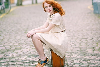 Redhead Woman Sitting on Vintage Suitcase on Cobblestone Street
