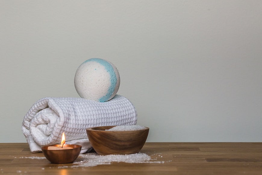 Spa relaxation setup with bath bomb, towel, and candle
