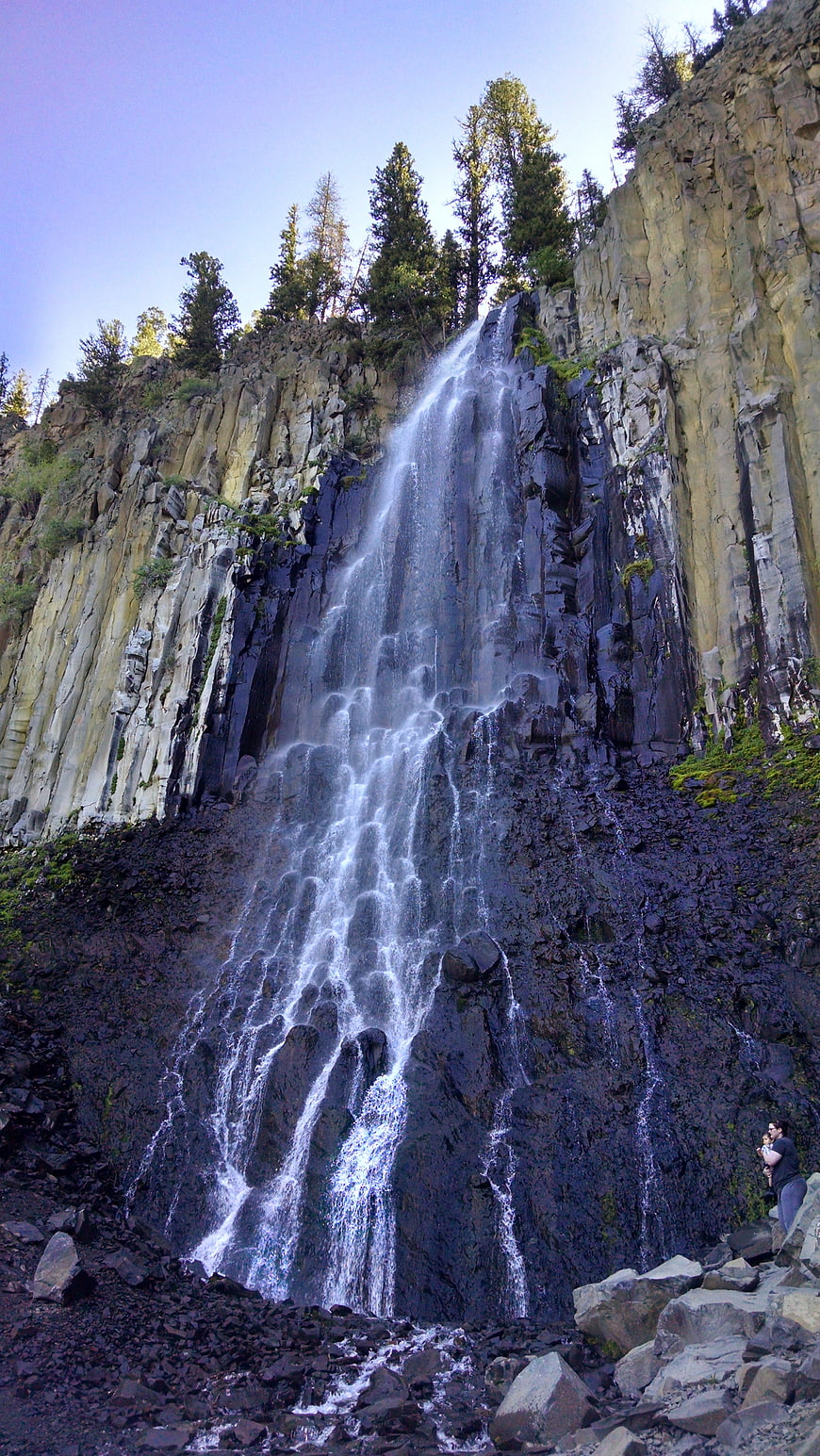 Tall waterfall cascading down dark volcanic rock cliffs