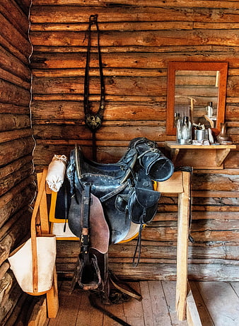 Vintage leather saddle and tack in rustic log cabin interior
