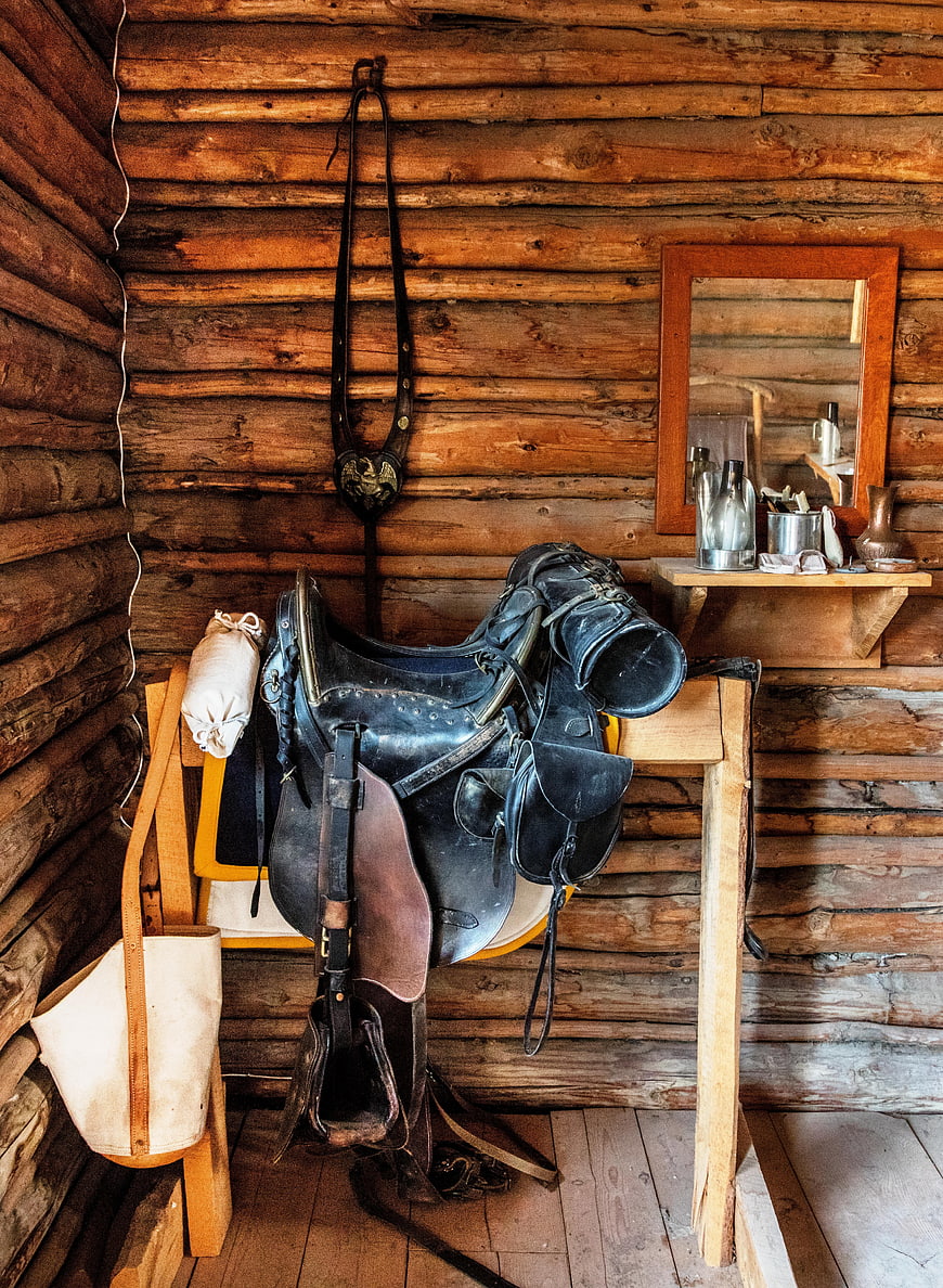 Vintage leather saddle and tack in rustic log cabin interior