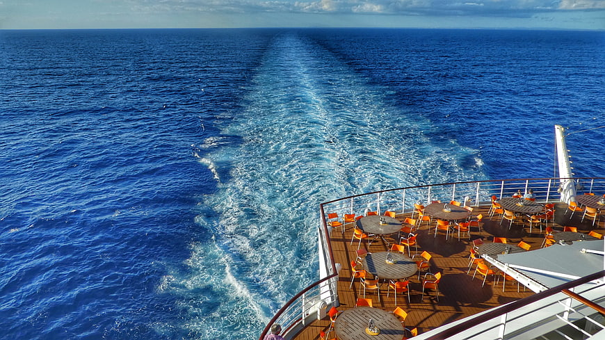 Cruise ship wake on blue ocean with deck seating