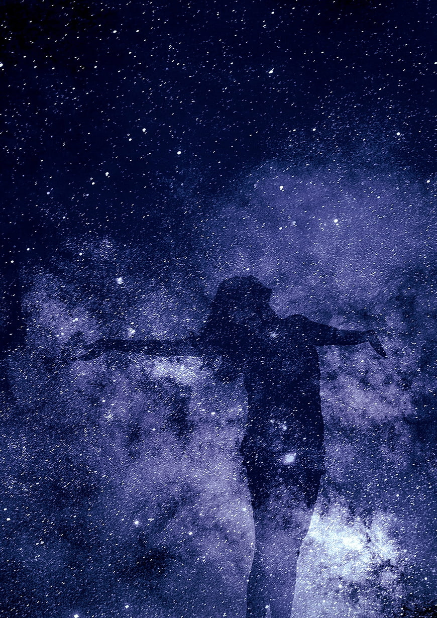 Silhouette of woman with arms outstretched against starry night sky