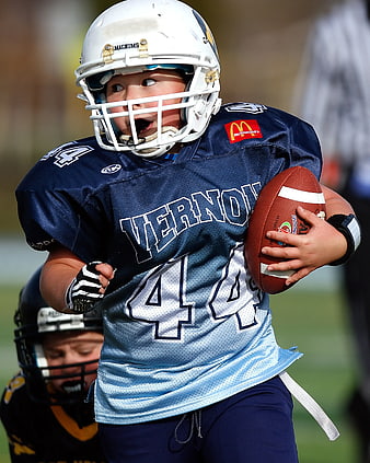Young Boy Running with Football in Blue Jersey