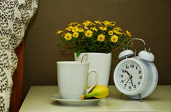 Cozy bedside still life with coffee, banana, flowers, and alarm clock