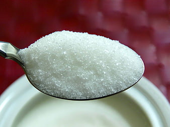 Close-up of white granulated sugar on a silver spoon