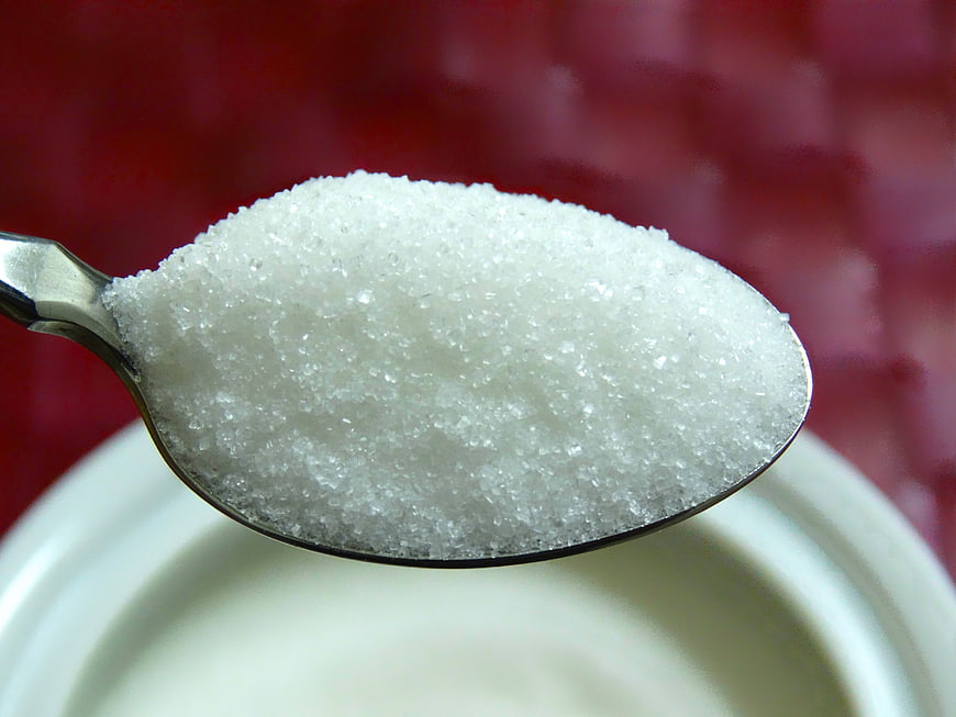 Close-up of white granulated sugar on a silver spoon