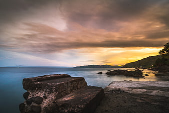 Dramatic Sunset Seascape with Rocky Foreground and Smooth Water