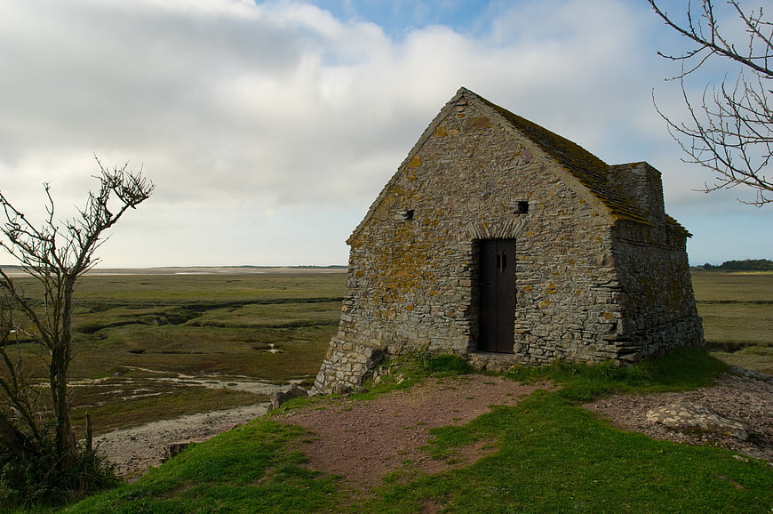 Old stone chapel on grassy hill overlooking marshland