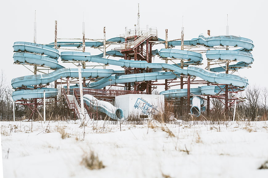 Abandoned blue water slide complex in snowy winter landscape