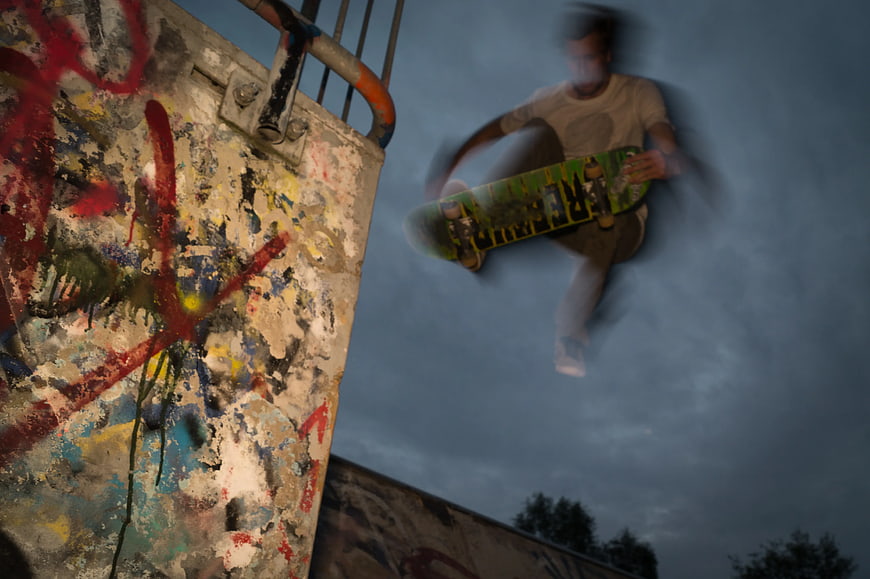Skateboarder performing trick against graffiti wall