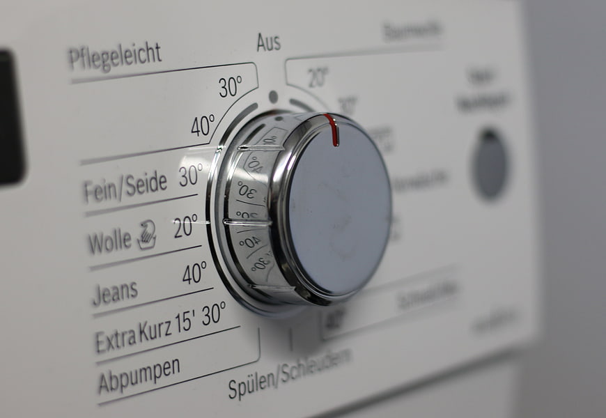 Close-up of washing machine control dial with German settings