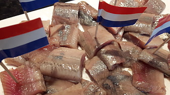 Raw herring steaks with Dutch flags on white plate