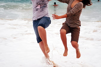 Two friends jumping in ocean waves at the beach