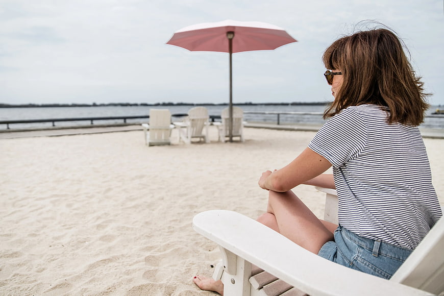Woman relaxing on white beach chair by the water