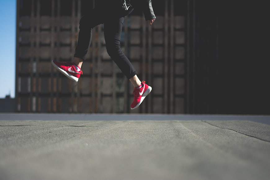 Red Sneakers Jumping on Rooftop with Urban Background