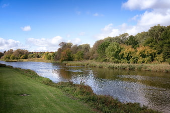 Serene River Landscape with Green Banks and Blue Sky