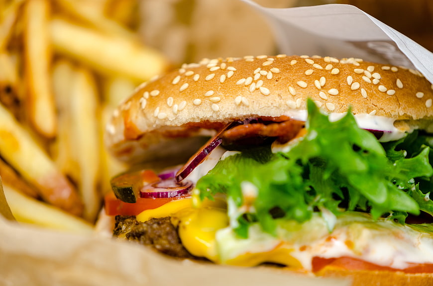 Close-up of a fresh beef burger with fries and vegetables