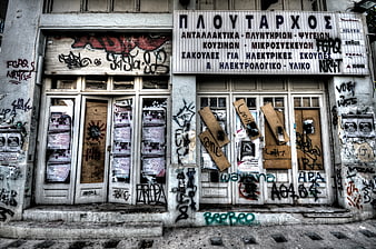 Abandoned Greek storefront with graffiti and boarded windows