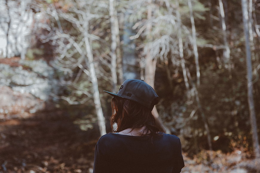 Woman in Baseball Cap Looking into Blurred Forest