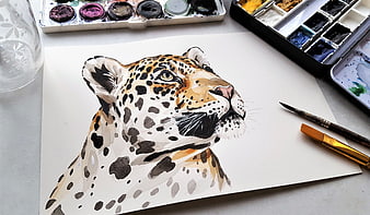 Watercolor painting of a jaguar head with art supplies