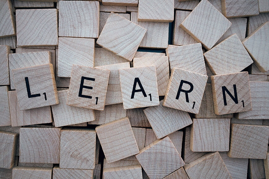 Wooden Scrabble Tiles Spelling Learn on Scattered Background