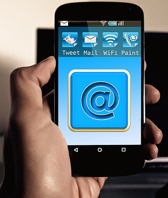 Hand holding smartphone with email app icon on screen