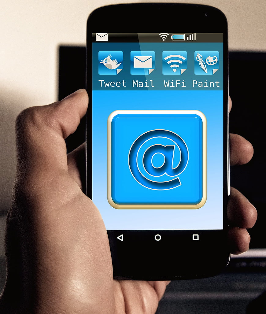 Hand holding smartphone with email app icon on screen
