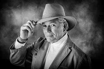 Black and white portrait of a senior man tipping a cowboy hat