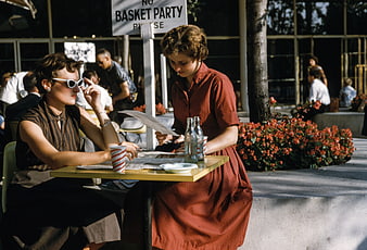 Two women reading newspaper at outdoor cafe table