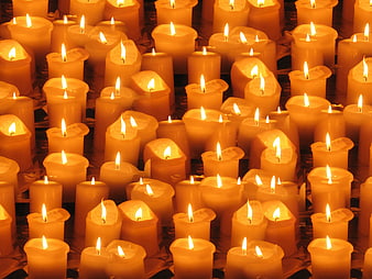 Close-up of many lit yellow candles with warm glowing flames