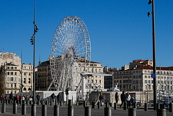 Large white Ferris wheel in Marseille port with blue sky
