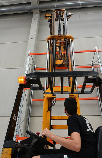 Warehouse worker operating forklift in industrial storage facility