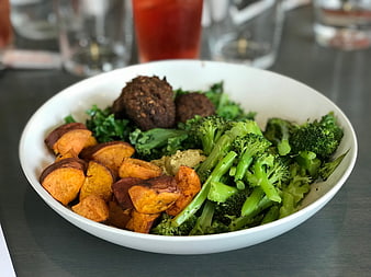 Healthy vegan bowl with roasted sweet potatoes, broccoli, and meatballs