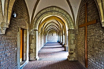 Historic Stone Cloister Corridor With Arched Vaults And Wooden Cross