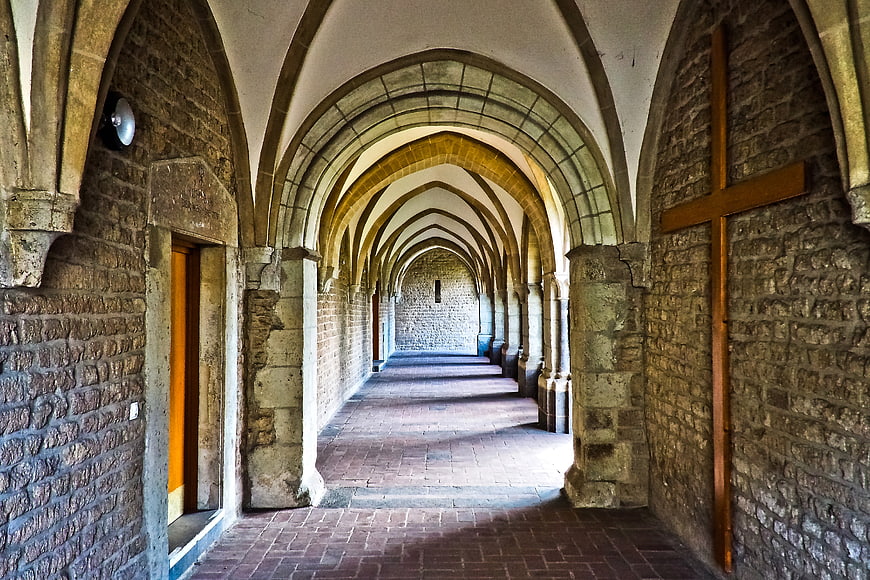 Historic Stone Cloister Corridor With Arched Vaults And Wooden Cross