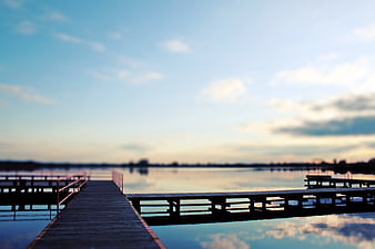 Serene wooden pier extending into calm lake at sunset