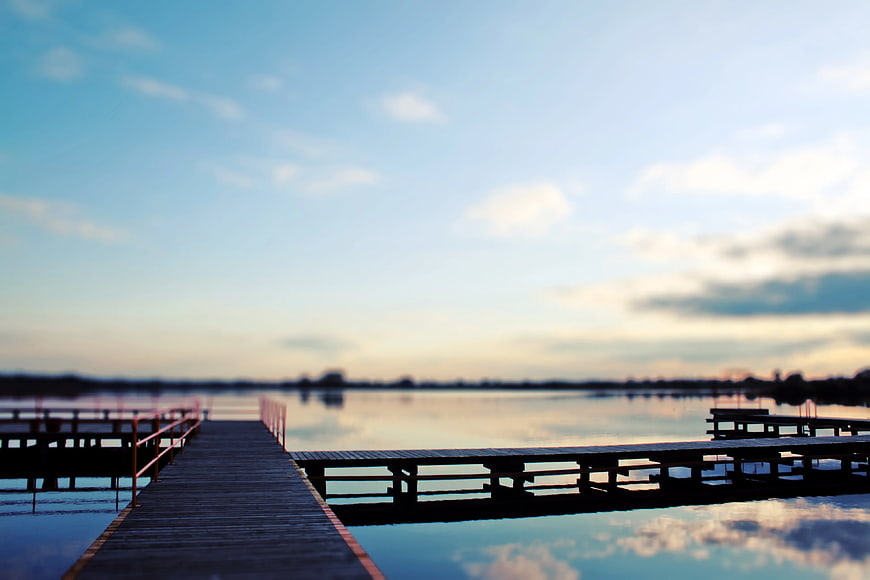 Serene wooden pier extending into calm lake at sunset