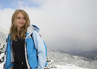 Young woman in blue jacket hiking in snowy mountains