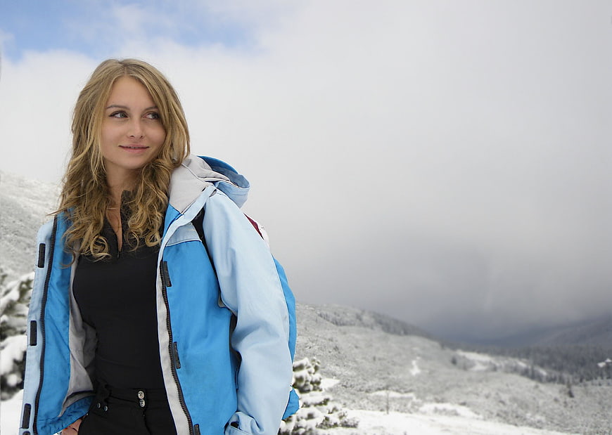 Young woman in blue jacket hiking in snowy mountains